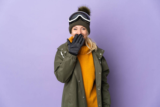 Skier Russian girl with snowboarding glasses isolated on purple background happy and smiling covering mouth with hand - 写真・画像