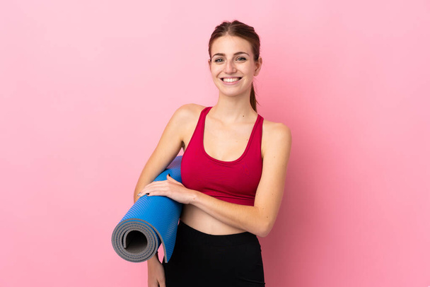 Jovem mulher esporte sobre isolado fundo rosa com um tapete e sorrindo - Foto, Imagem