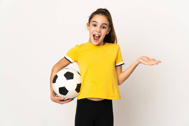 Маленькая девочка футболист изолирован на белом фоне с шокированным выражением лица - Фото, изображение