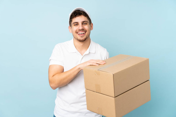 Delivery caucasian man isolated on blue background laughing - Valokuva, kuva