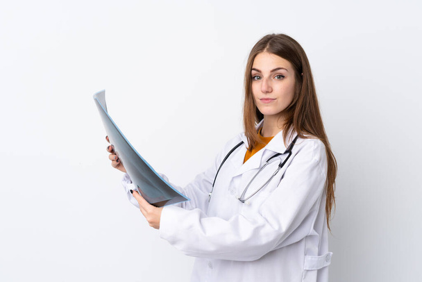 Giovane donna su sfondo isolato indossando un abito medico e tenendo una scansione ossea - Foto, immagini