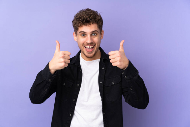 Caucasian man isolated on purple background giving a thumbs up gesture - 写真・画像