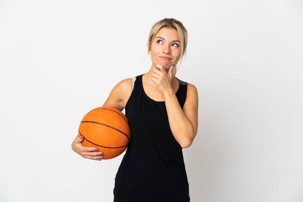 Young Russian woman playing basketball isolated on white background and looking up - Fotó, kép