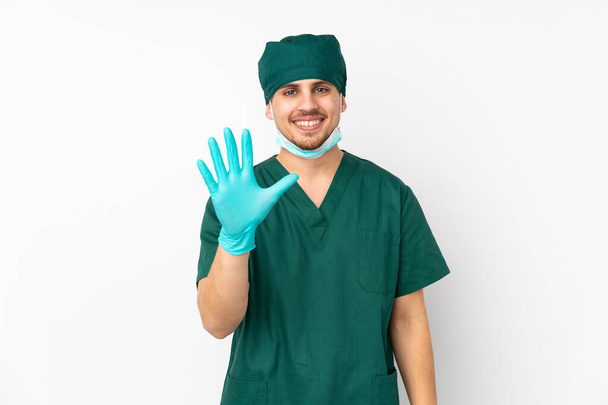 Surgeon in green uniform isolated on isolated white background counting five with fingers - 写真・画像