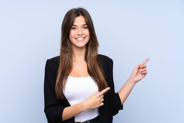 Young Brazilian business woman over isolated blue background pointing finger to the side - Photo, Image