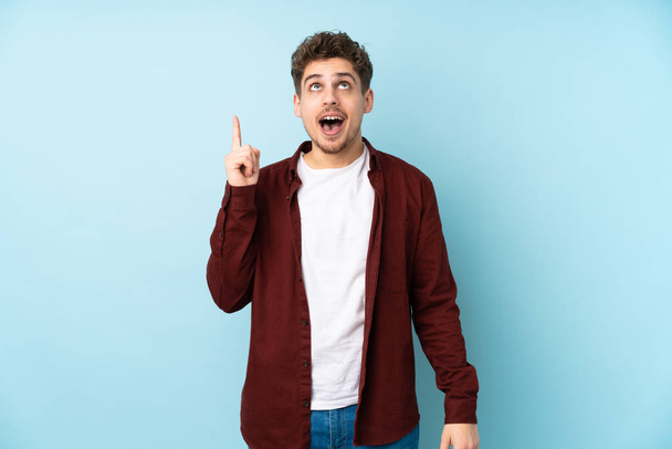 Young caucasian man isolated background pointing up and surprised - Fotoğraf, Görsel