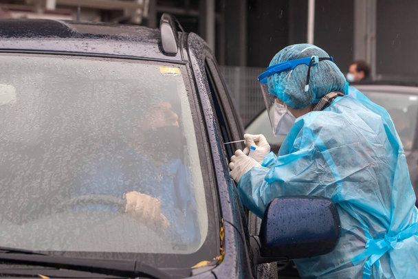 Thessaloniki, Greece - December 10, 2020. A medical worker wearing special suit to protect against coronavirus, conduct a "drive through" rapid testing for covid-19 - Foto, Imagen