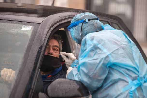 Thessaloniki, Greece - December 10, 2020. A medical worker wearing special suit to protect against coronavirus, conduct a "drive through" rapid testing for covid-19 - Foto, Imagem