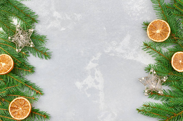 Christmas frame composition with fir tree branches and dry oranges on grey concrete background. Top view, flat lay, copy space. - Φωτογραφία, εικόνα