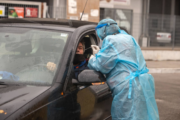 Saloniki, Grecja - 10 grudnia 2020. Pracownik medyczny w specjalnym garniturze do ochrony przed koronawirusem, przeprowadzi szybkie testy na obecność kovidu-19 - Zdjęcie, obraz