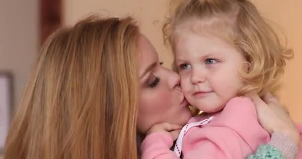 Joven hermosa madre besa a su hija en la mejilla - Imágenes, Vídeo