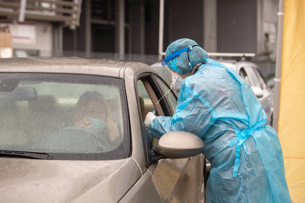 Thessaloniki, Greece - December 10, 2020. A medical worker wearing special suit to protect against coronavirus, conduct a "drive through" rapid testing for covid-19 - Φωτογραφία, εικόνα