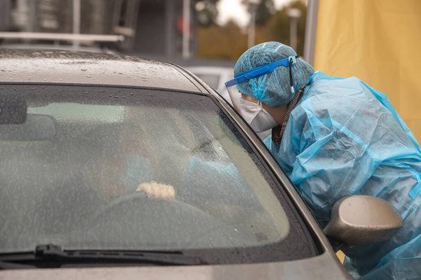 Thessaloniki, Greece - December 10, 2020. A medical worker wearing special suit to protect against coronavirus, conduct a "drive through" rapid testing for covid-19 - Photo, image