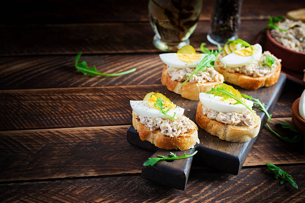 Toasted bread with a salted codfish mousse on wooden cutting board. Mackerel paste on toasts from fried bread.  Scandinavian cuisine - Photo, Image
