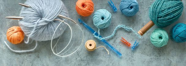 Various wool yarn and knitting needles, creative knitting hobby. Panoramic background in pastel colors on textured grey green background. - Foto, Bild