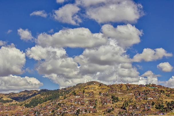 Hillside γεμάτη από σπίτια ταπεινών οικογενειών με ραδιόφωνο, τηλεόραση και τηλεφωνικές κεραίες στην κορυφή και ένα μπλε ουρανό με λευκά σύννεφα - Φωτογραφία, εικόνα