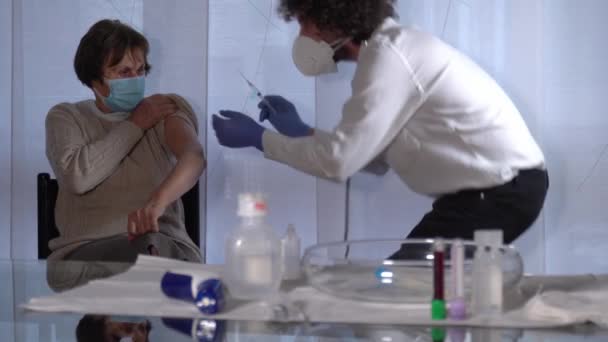 Європа, Італія, Мілан - лікар відвідує стареньку жінку і перевіряє її вакцину під час карантинного будинку Ковід-19. - Кадри, відео