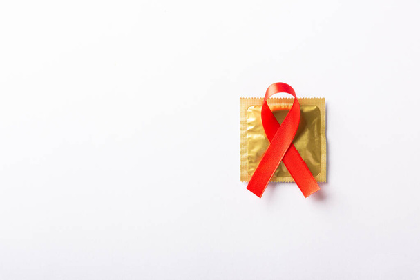 Red bow ribbon symbol HIV, AIDS cancer awareness and condom with shadows, studio shot isolated on white background, Healthcare medicine sexually concept, World AIDS Day - Fotografie, Obrázek