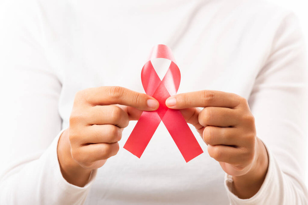 Female holding HIV AIDS awareness red ribbon on hands in studio shot isolated on over white background, Healthcare and medicine, World aids day concept - 写真・画像