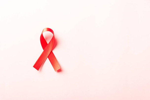 Red bow ribbon symbol HIV, AIDS cancer awareness with shadows, studio shot isolated on pink background, Healthcare medicine concept, World AIDS Day - Photo, image