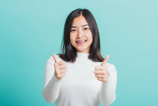 Young beautiful Asian woman cheerful smiling showing finger thumb up, Portrait happy female using showing like the gesture for good sign, studio shot isolated on a blue background - Fotó, kép