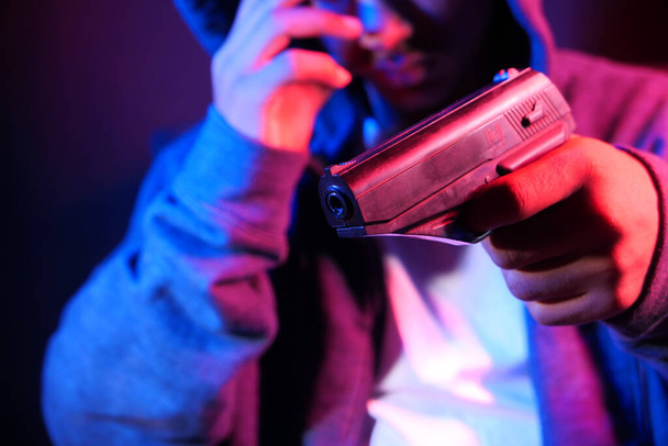 hooded man hand holding gun isolated on black  - Photo, Image