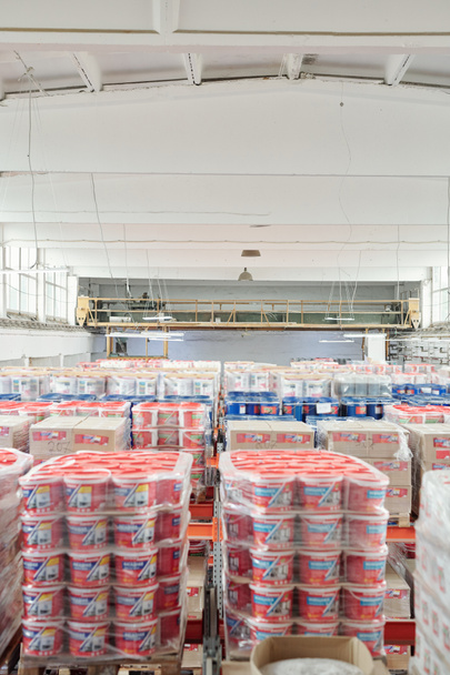 Interieur des zeitgenössischen Lagerraums des modernen Gebäudes beliefert den Verbrauchermarkt mit vielen Stapeln von Plastikeimern mit Farben und Boxen - Foto, Bild