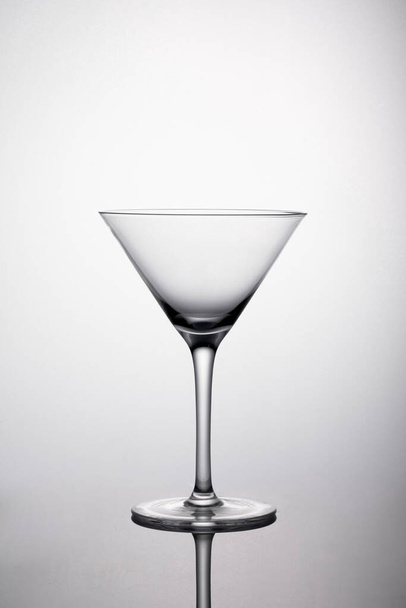 Un colpo verticale di un bicchiere da martini con ombra su sfondo bianco - Foto, immagini