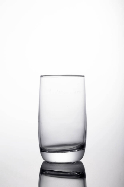 A vertical shot of glass for water on a reflecting surface - Photo, Image