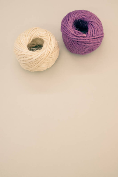 A vertical shot of purple and beige yarns isolated on a beige background - Foto, Imagem