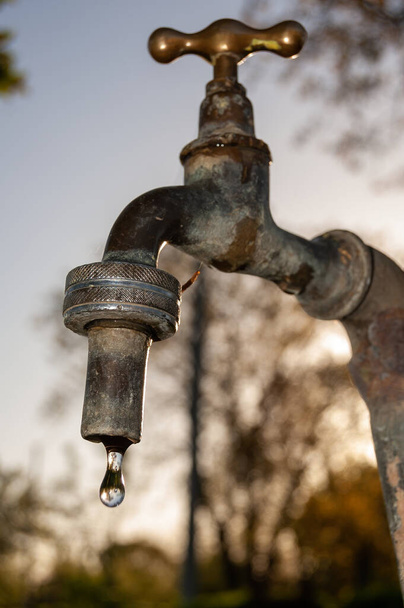 A vertical closeup shot of rusted metal faucet with a water drop - Fotografie, Obrázek