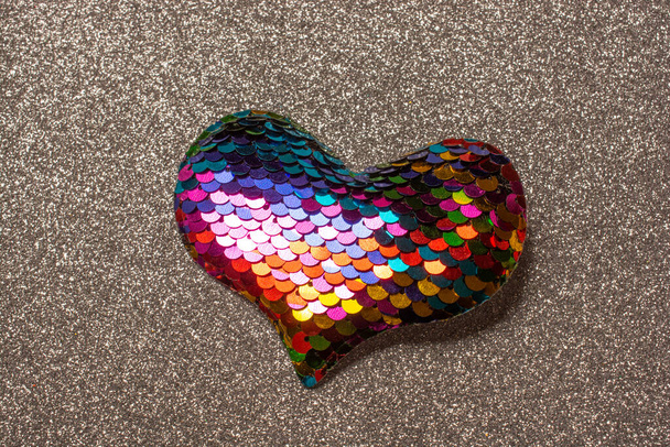 A top view of a heart shape fabric with decorative colorful sequin on a textured background - Foto, immagini