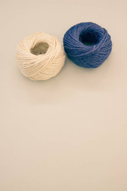 A vertical shot of blue and beige yarns isolated on a beige background - Foto, afbeelding