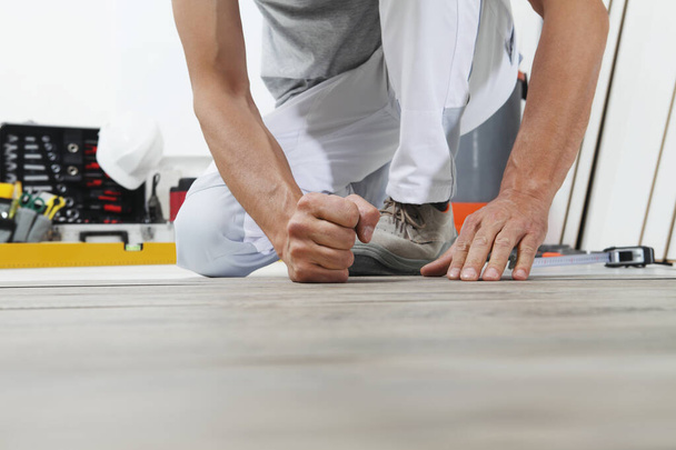 Worker hands installing timber laminate vinyl floor. Wooden floors house renovation. - Photo, Image