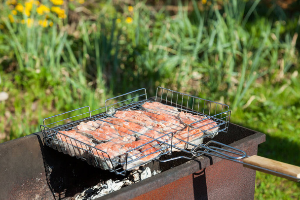 Draufsicht auf die gebräunten Steaks von rotem Coho-Lachs, die an einem Sommertag auf dem Land in einem Grill auf Holzkohle gebraten werden. Kochen eines gesunden Grillabendessens im Freien. - Foto, Bild