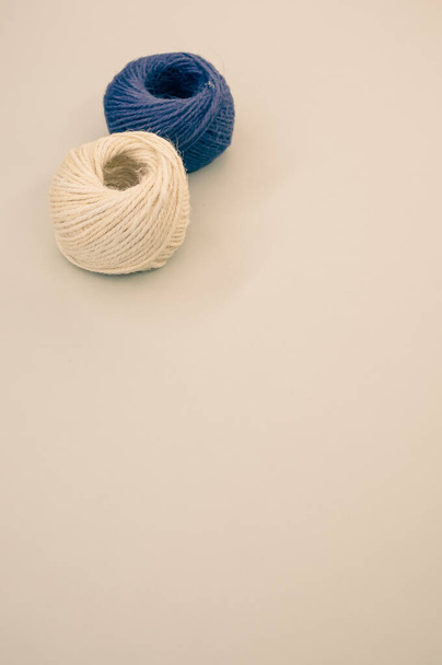 A vertical shot of blue and beige yarns isolated on a beige background - Φωτογραφία, εικόνα