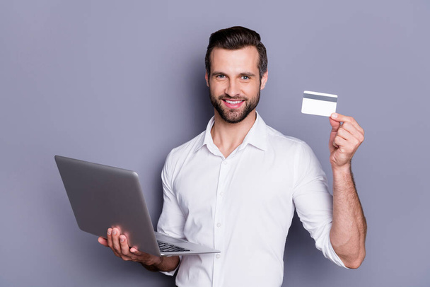 Stay home pay purchase with bank service. Positive manager ceo agent man work remote use laptop need buy food hold show credit debit card wear white shirt isolated over grey color background - Foto, Imagem