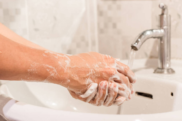 Facet myje ręce mydłem nad zlewem w łazience. Koncepcja higieny. - Zdjęcie, obraz