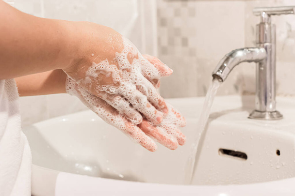 Kadın ellerini banyodaki lavabonun üzerinde sabunla yıkıyor. Hijyen tedavisi kavramı. - Fotoğraf, Görsel