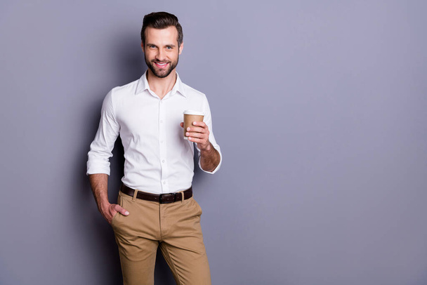 Portrait of positive cheerful man real estate agent economist hold takeaway cup with latte cappuccino enjoy working day rest wear white trousers isolated over gray color background - Fotoğraf, Görsel