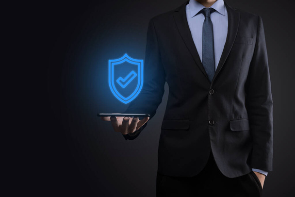 Védelmi hálózat biztonsági számítógép kezében egy üzletember. üzleti, technológia, kiberbiztonság és internet koncepció - üzletember nyomkodja a pajzs gombot a virtuális képernyőn Adatvédelem. - Fotó, kép