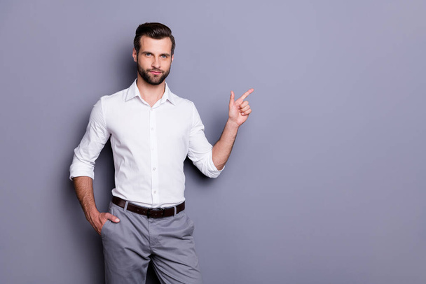 Portrait of confident representative investor man point index finger copyspace demonstrate ads promotion look attention wear white shirt pants isolated over gray color background - Foto, afbeelding
