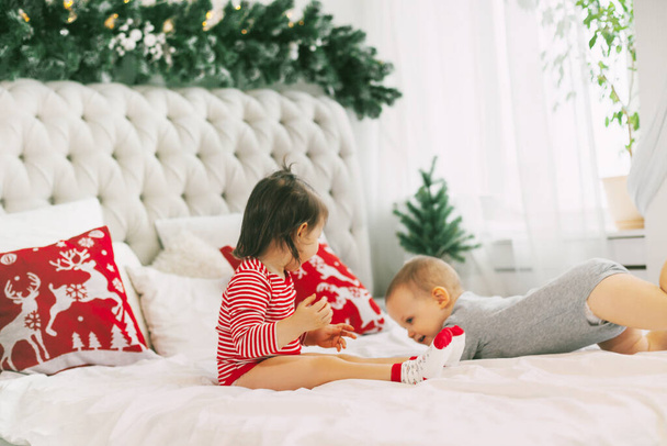 A little boy and girl play on their parents  bed on Christmas morning. Family morning on a snowy cold Christmas day - Фото, зображення