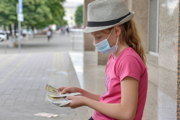 Egy fiatal lány védőruhában, egydollárosokat számol.. - Fotó, kép