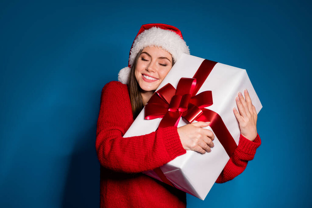 Photo of positive girl in santa claus headwear hug big white gift box enjoy x-mas christmas jolly holy celebrate wear pullover isolated over gradient blue color background - Foto, immagini
