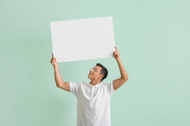 Junger Mann mit leerem Plakat auf farbigem Hintergrund - Foto, Bild