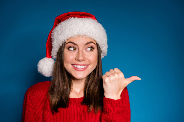Close up photo positive girl in santa claus hat point forefinger copyspace present x-mas newyear magic fairy ads promo wear sweater pullover isolated blue gradient color background - 写真・画像