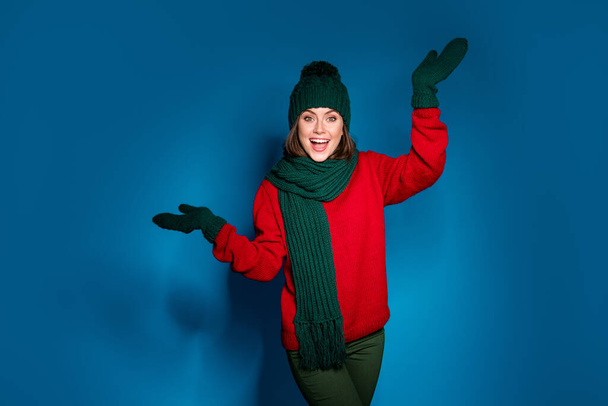Photo of crazy girl in warm woolen hat scarf hold hand catch air fly fall snow flakes mittens wear sweater pullover pants trousers isolated over gradient blue color background - 写真・画像