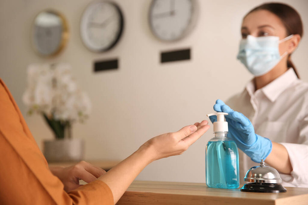 Woman applying antiseptic gel at hotel reception, closeup - Photo, Image