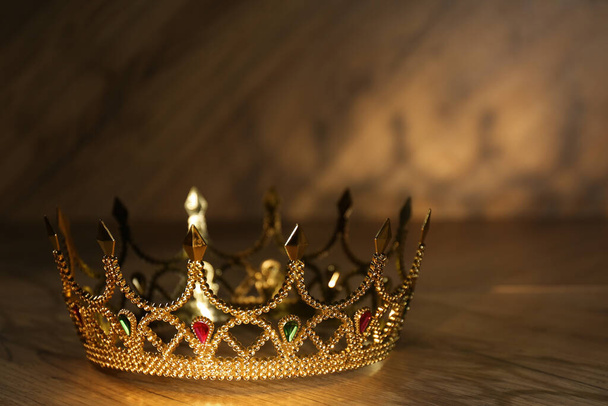 Beautiful golden crown with gems on wooden table. Fantasy item - Valokuva, kuva